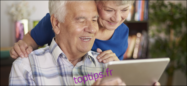 Couple de personnes âgées souriant tout en jouant avec une tablette