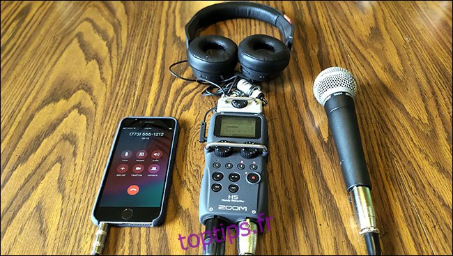 Un iPhone, un microphone Shure SM58 et des écouteurs tous connectés à un enregistreur H5 Zoom, posé sur une table.