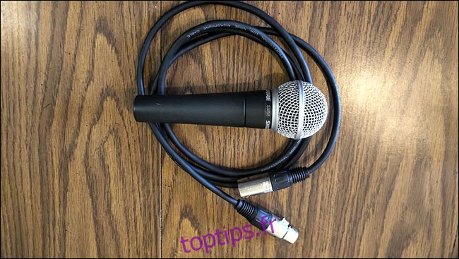 Un microphone Shure SM58 posé sur un câble XLR AmazonBasics sur une table.