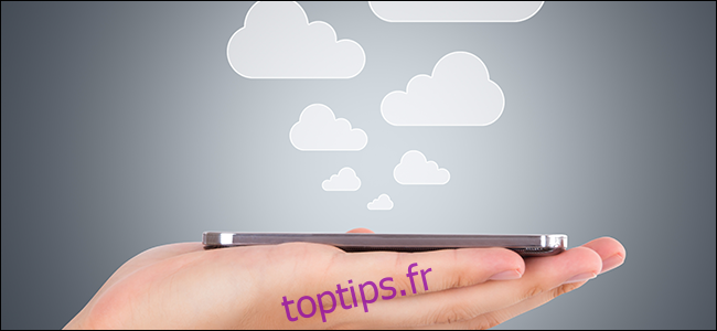 Une main tenant un téléphone alors que des nuages ​​en sortent, symbolisant les fichiers enregistrés dans le cloud.