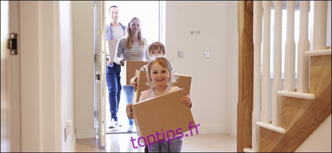 Une famille heureuse transportant des boîtes dans une maison.