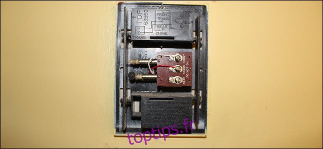 Un carillon avec le câblage exposé, un fil rouge sur la borne trans et blanc sur la borne avant.