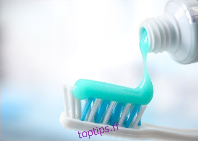 Le dentifrice est éjecté d'un tube sur une brosse à dents.