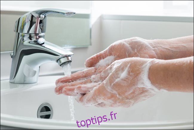 Se laver les mains avec du savon sous un robinet d'eau.