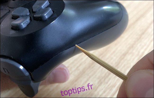 Un cure-dent nettoyant la couture sur un contrôleur DualShock 4.