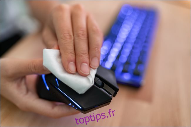 Une main essuyant une souris d'ordinateur avec un chiffon.