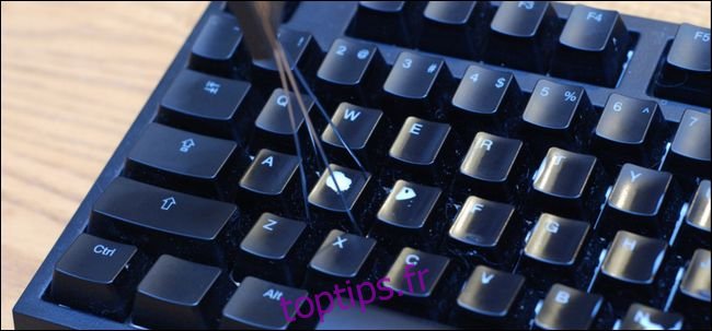 Un outil de suppression de keycap se prépare à supprimer une touche d'un clavier.