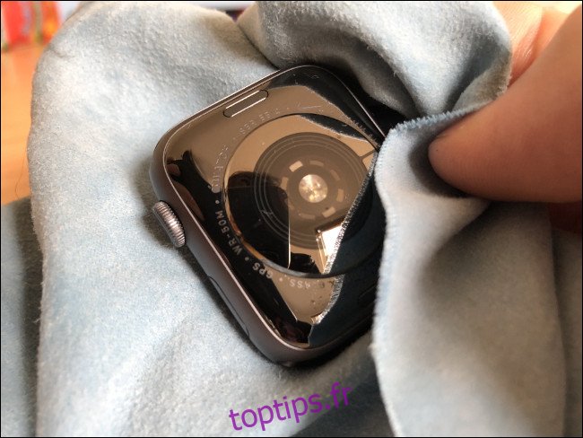 Une main essuyant une Apple Watch avec un chiffon.