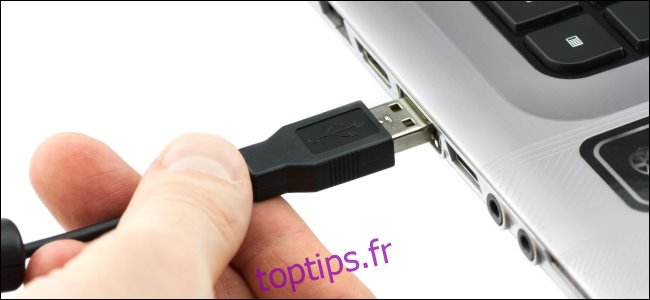 Une main branchant un câble USB Type-A sur un ordinateur portable.