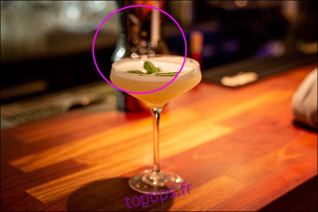 Un verre à cocktail sur un bar avec bokeh polygonal au milieu. 
