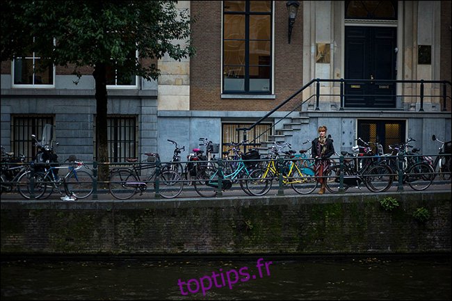 Une femme debout sur un pont derrière une file de vélos garés.