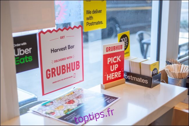 Signes pour GrubHub, Postmates et Uber Eats dans un restaurant.