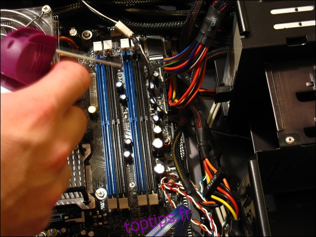 Une main tenant une canette d'air comprimé sur un boîtier d'ordinateur ouvert. 