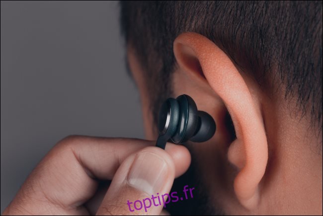 Un homme insère un écouteur dans son oreille.