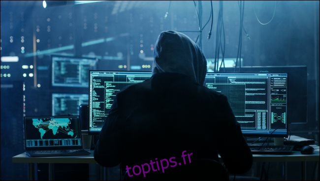Un hacker ténébreux dans un sweat à capuche assis devant un ordinateur.
