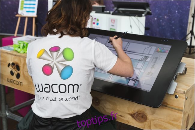 Un artiste numérique travaillant sur une grande tablette Wacom.