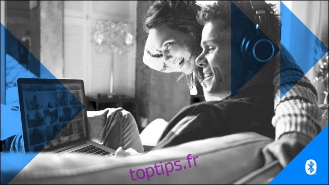 Un homme et une femme portant des écouteurs tout en regardant un écran d'ordinateur portable.